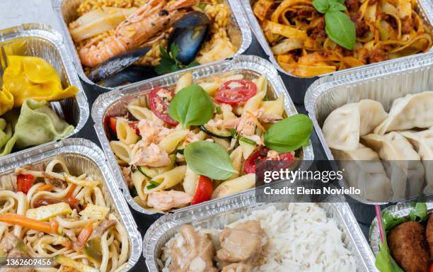 food delivery.  takeaway food,  different aluminium lunch box with dumplings, noodles with chicken, rice with chicken, pasta with salmon, falafel - plane food stock pictures, royalty-free photos & images