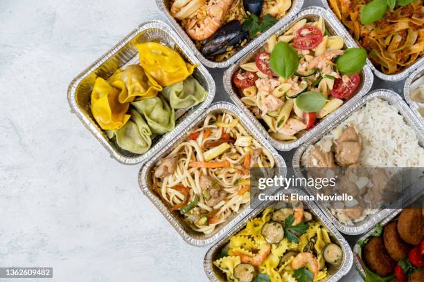 food delivery. takeaway food, different aluminium lunch box with dumplings, noodles with chicken, rice with chicken, pasta with salmon, falafel - cibo precotto foto e immagini stock