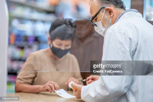 picking up prescription medicine at the pharmacy - pharmacy mask stock pictures, royalty-free photos & images