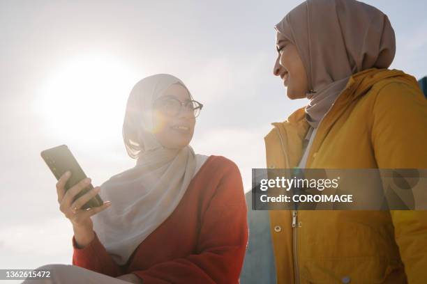 young arab female friends talking and enjoying time together outdoors. - middle east friends stock pictures, royalty-free photos & images