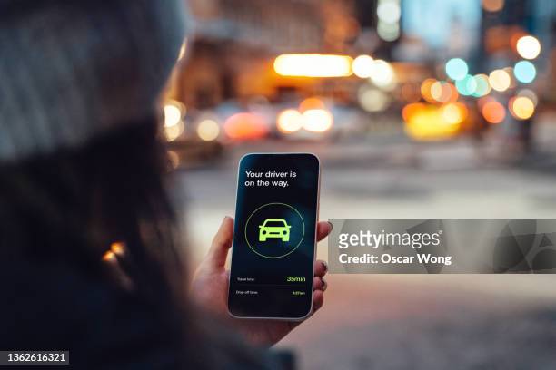 young woman ordering a taxi ride with mobile app on smart phone - mobile apps stockfoto's en -beelden