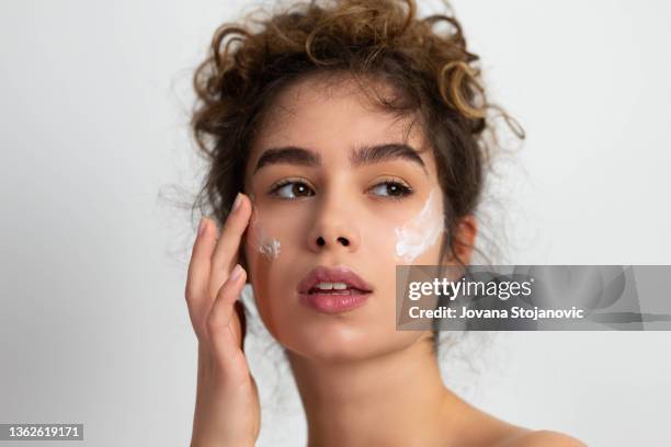美しい若い女性が彼女の顔を育てる - 乳液 ストックフォトと画像
