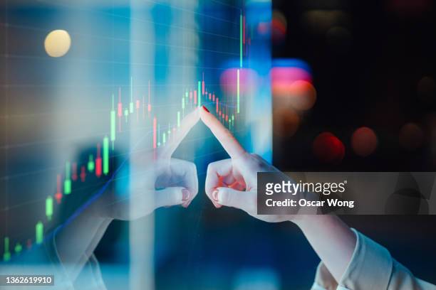 businesswomen touching stock market graph on a virtual screen display - trading board stock-fotos und bilder