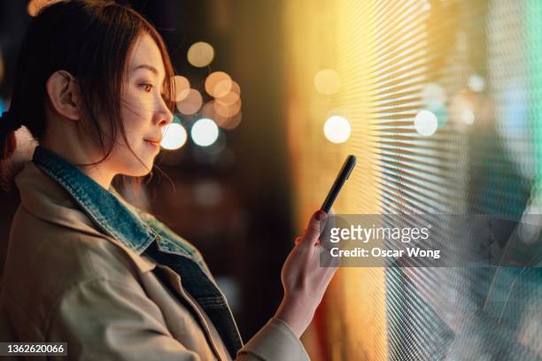 young woman using crypto investment app on smart phone - blockchain crypto fotografías e imágenes de stock