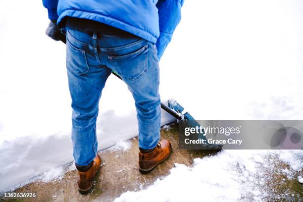 man shovels snow from driveway after winter storm - snow shovel stock-fotos und bilder