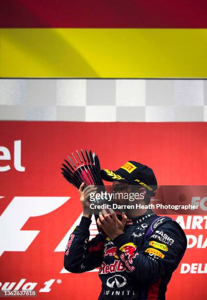 Fire protection suit wearing, German Red Bull Racing driver Sebastian Vettel raising kissing the race winners trophy in celebration of winning the...