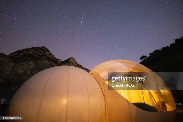 Shooting star of the Geminid meteor shower is pictured above tents on January 3, 2022 in Beijing, China.