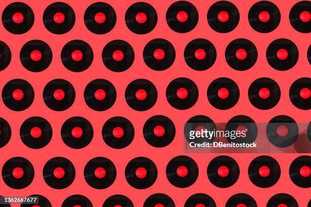 music black vinyl records pattern with red label on red background. music, disco, sound, retro, vintage, analog and analog record concept. - vintage record player no people stock-fotos und bilder