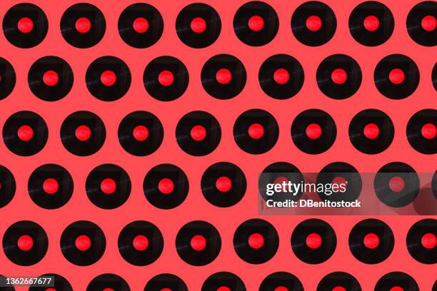 music black vinyl records pattern with red label on red background. music, disco, sound, retro, vintage, analog and analog record concept. - record player fotografías e imágenes de stock