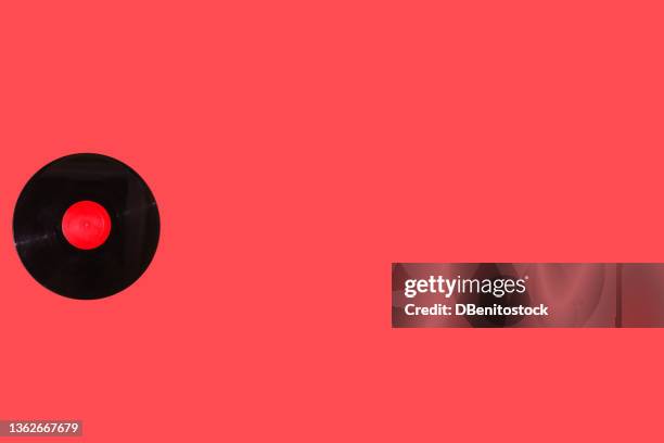 music vinyl record with red label, on the left side, on red background. music, disco, sound, retro, vintage, analog and analog record concept. - lp fotografías e imágenes de stock