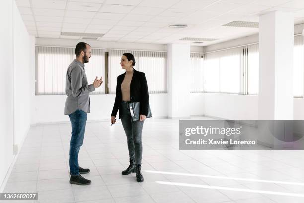 young adult man discussing with a real estate female agent while visiting a new office space for rental - real estate office stockfoto's en -beelden