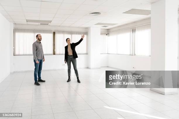 female real estate agent showing new office space for rent to a businessman. - house viewing stock pictures, royalty-free photos & images