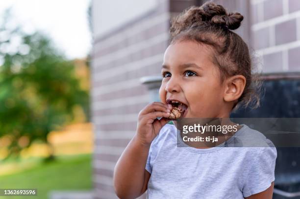 süßes kleines mädchen isst schokoriegel - candy bar stock-fotos und bilder