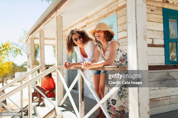 mother and adult daughter relaxing on sunny beach hut patio - beach hut stock pictures, royalty-free photos & images