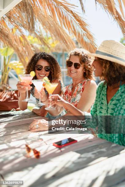 mother and adult daughters drinking cocktails at sunny beach bar - 4 cocktails stockfoto's en -beelden