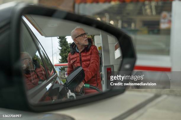 senior man refueling his car at the gas station - gas station imagens e fotografias de stock