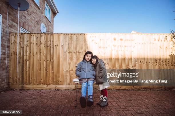 lovely cheerful little sister smiling joyfully at the camera in the garden of their new house - family with two children british stock pictures, royalty-free photos & images