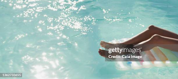 carefree young woman on pool raft in sunny, tranquil swimming pool - luftmatratze von oben stock-fotos und bilder