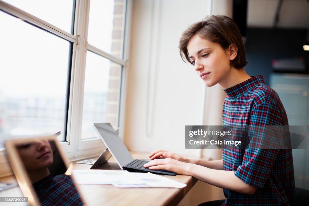 Businesswoman working at digital tablet in office window