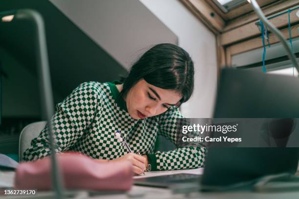 hispanic college student doing some home works from home with laptop - student girl using laptop computer and smart phone stock-fotos und bilder
