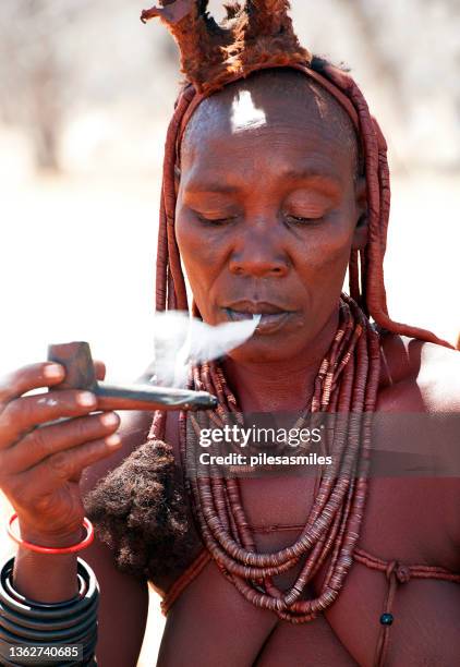 old himba woman exhales from her pipe, himba tribal village, damaraland, namibia, southern africa - african tribal face painting 個照片及圖片檔