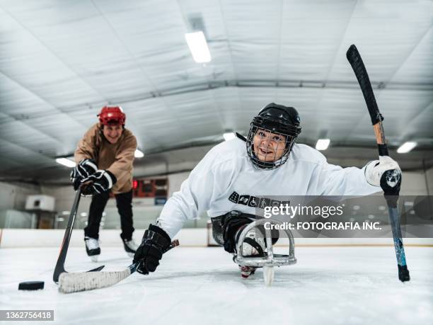 mature disabled latin woman and her trainer practising sledge hockey - hockey coach stock pictures, royalty-free photos & images