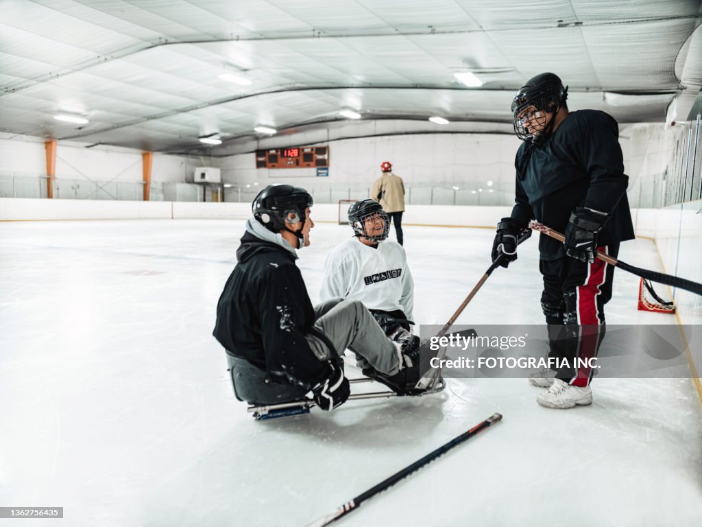 Mature Disabled Latin woman with her family and friends practising sledge hockey