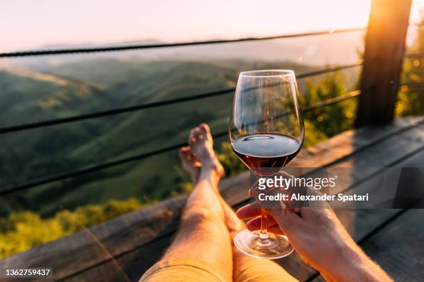 man drinking wine with mountains view, personal perspective (pov) - sunlight through drink glass foto e immagini stock