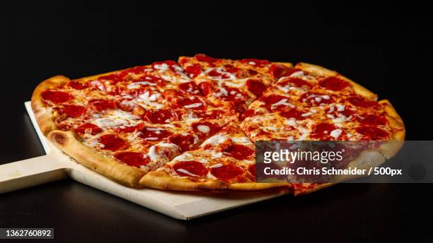 italian food,close-up of pizza on table against black background,massachusetts,united states,usa - pepperoni pizza stockfoto's en -beelden