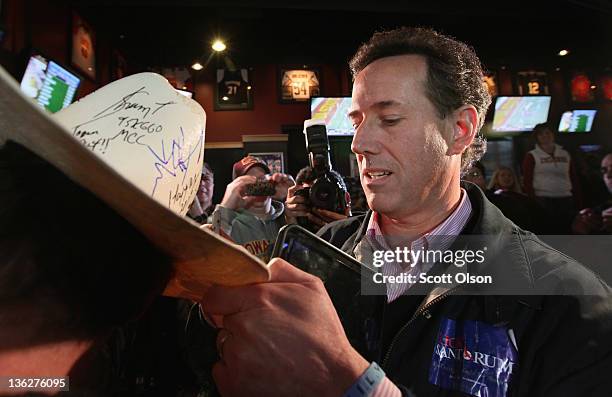 Republican presidential candidate former U.S. Senator Rick Santorum signs a hat as he arrives for a Pinstripe Bowl watch party at Buffalo Wild Wings...
