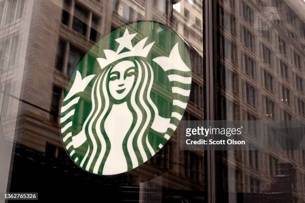 Starbucks logo hangs in the window of one of the chain's coffee shops in the Loop on January 04, 2022 in Chicago, Illinois. Workers at the coffee...
