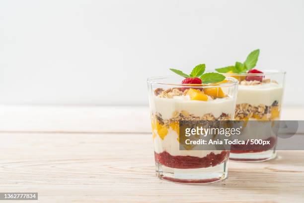 homemade mango and raspberry with yogurt and granola - mango smoothie stock pictures, royalty-free photos & images