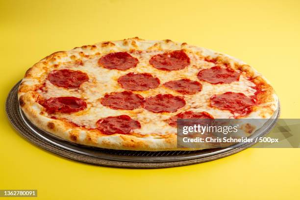 american food,high angle view of pizza in plate on yellow background,rhode island,united states,usa - pepperoni pizza stockfoto's en -beelden