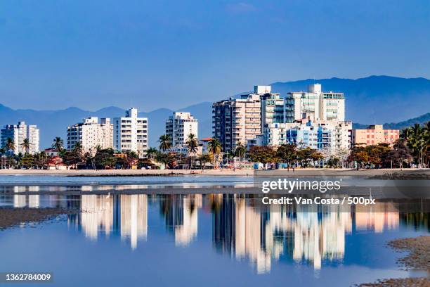 o reflexo,scenic view of lake by buildings against blue sky,caraguatatuba,brazil - reflexo stock pictures, royalty-free photos & images