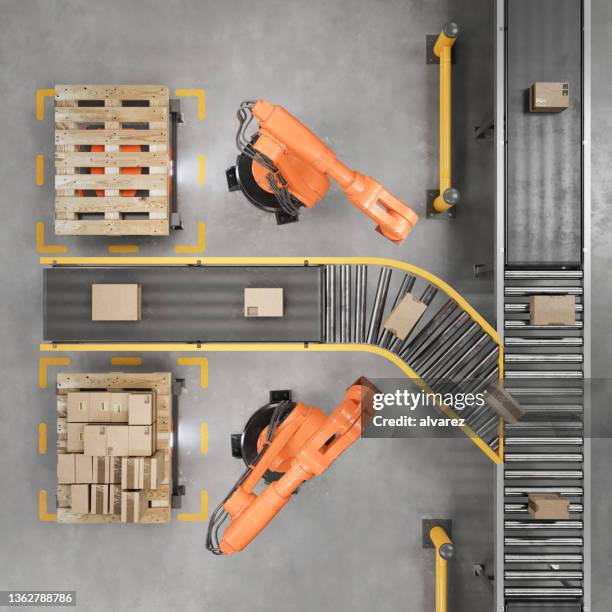 robot industriali che lavorano su un nastro trasportatore in un magazzino intelligente - packaging foto e immagini stock