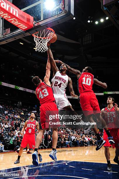 Marvin Williams of the Atlanta Hawks shoots against Kris Humphries and Damion James of the New Jersey Nets on December 30, 2011 at Philips Arena in...