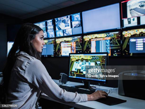 mixed race security guard watching monitors in control room - 管制室 ストックフォトと画像