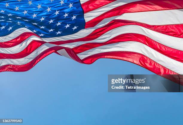low angle view of american flag waving in wind against clear sky - amerikaanse vlag stockfoto's en -beelden