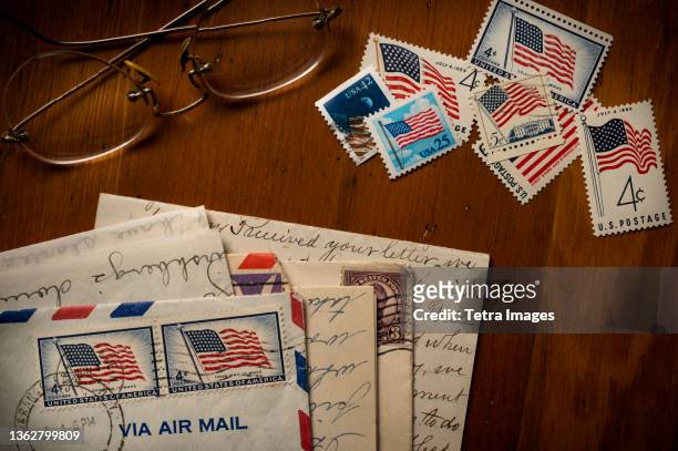 letters with american flag postage stamps on table - reading glasses on table stock pictures, royalty-free photos & images