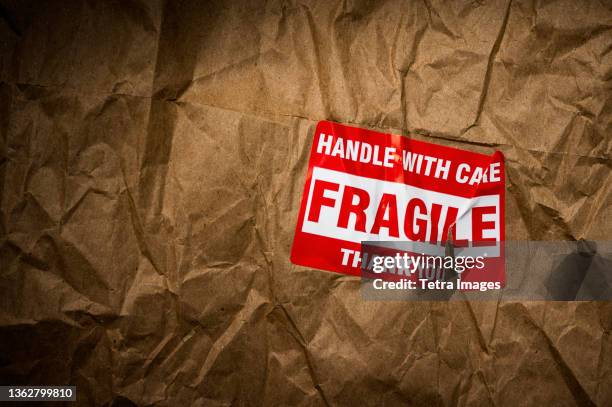 fragile handle with care sticker on crushed package - fragile sign stock pictures, royalty-free photos & images