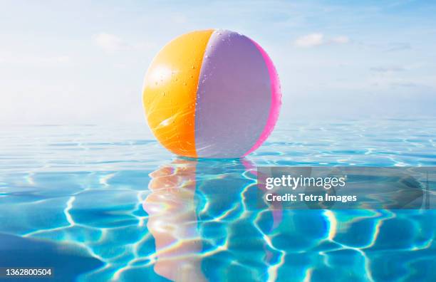 beach ball floating on calm water surface - beach ball pool stock pictures, royalty-free photos & images