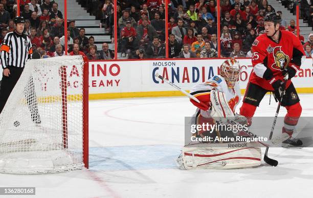 Chris Neil of the Ottawa Senators looks on as the puck hits the back of the net behind Leland Irving of the Calgary Flames for the overtime winner on...