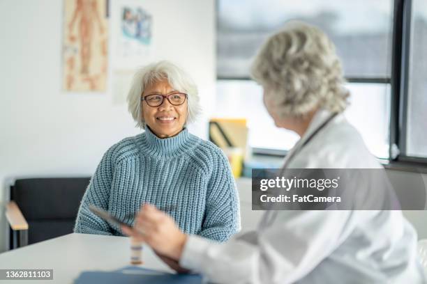 patient receiving her test results - mature adult with doctor stock pictures, royalty-free photos & images