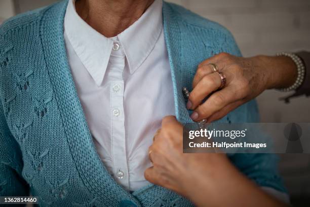 cropped image of senior woman pinning a brooch on her friends sweater. - brooch stock pictures, royalty-free photos & images