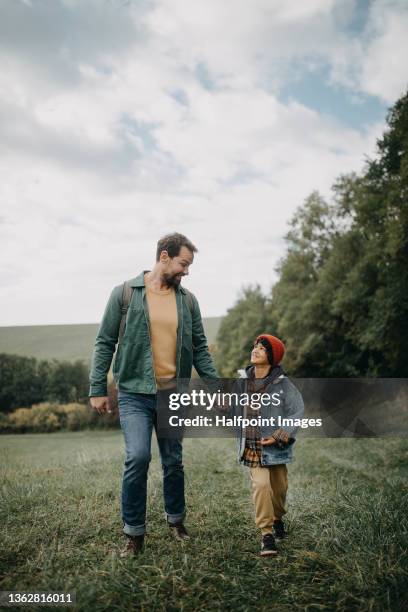 father and  small son holding hands and talking on walk in autumn nature. - family vertical stock pictures, royalty-free photos & images