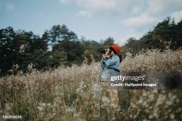little boy standing on a hill and looking through binoculars in autumn day. - bird watching stock pictures, royalty-free photos & images