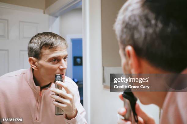 man trims facial hair in bathroom mirror - pink shaver stock pictures, royalty-free photos & images