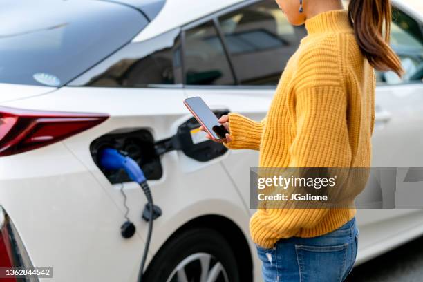 close up of mobile phone with electric car - recharging stock pictures, royalty-free photos & images