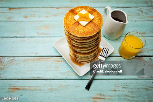 big tall stack of pancakes on a blue picnic background - big country breakfast stockfoto's en -beelden