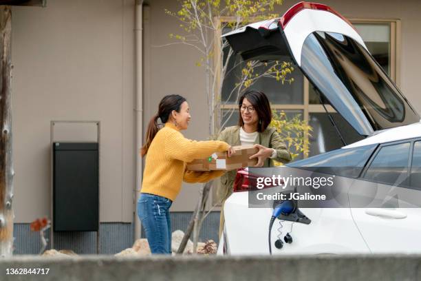 mujeres medianas adultas descargando un coche eléctrico - unloading fotografías e imágenes de stock